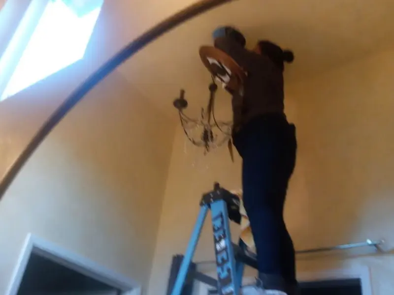 Electrician installing a chandelier in a Cliffside Park residence